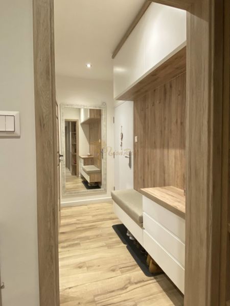 The entrance hall of a 3-room apartment with a wooden decor floor and a mirror on the wall.