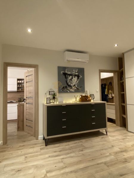 A spacious hallway with furniture, air conditioning, and a wooden decor floor in a 3-room apartment.