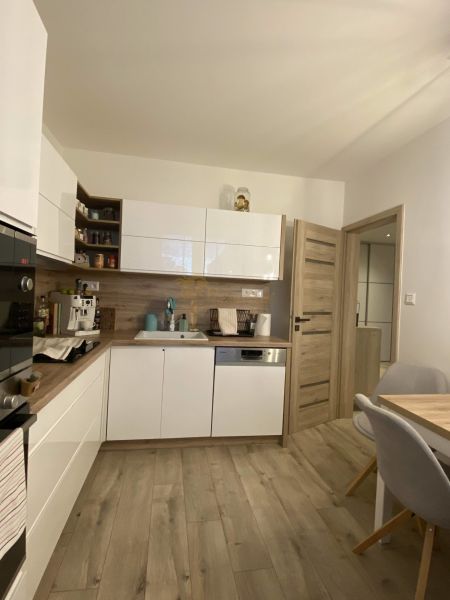 A kitchen with white cabinets, wooden decor, and a dining table in a 3-room apartment.