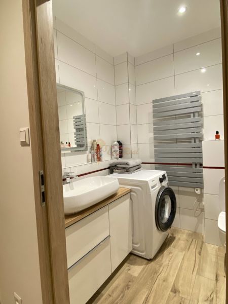 Bathroom in a 3-room apartment with a washing machine and a floor with a wooden decor.