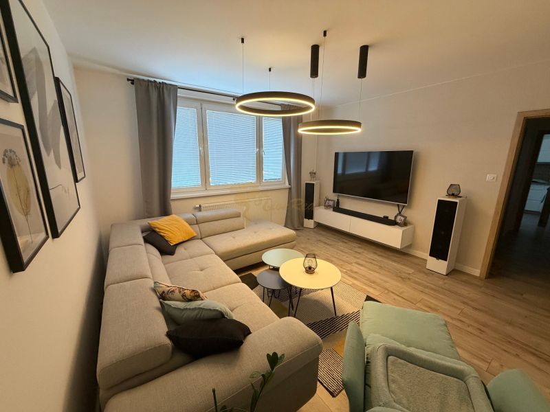Living room with a comfortable sofa, television, and floor with wooden decor, 3-room apartment.