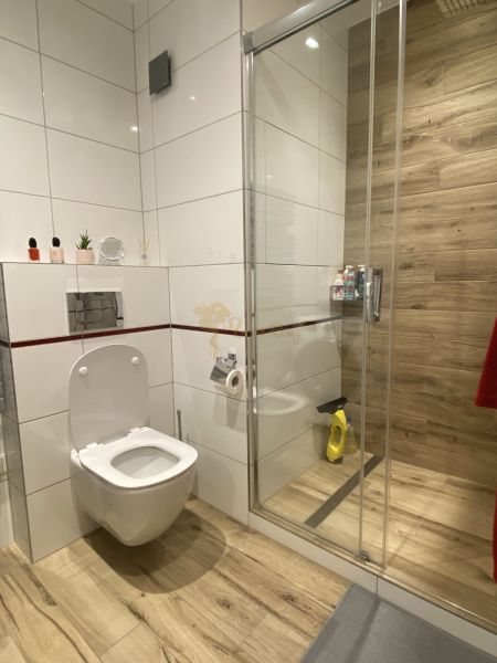 A bathroom in a 3-room apartment with a wooden decor floor and a shower corner.