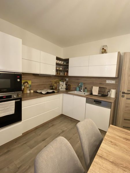 A kitchen in a 3-room apartment with white cabinets and a wood-patterned floor.