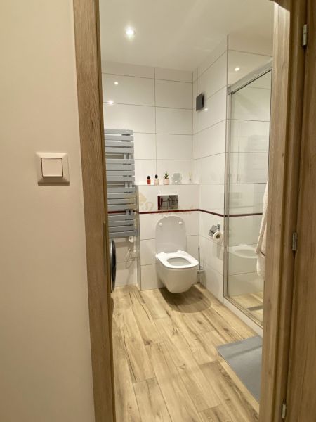 Bathroom with toilet and shower in a 3-room apartment, floor with wooden decor.