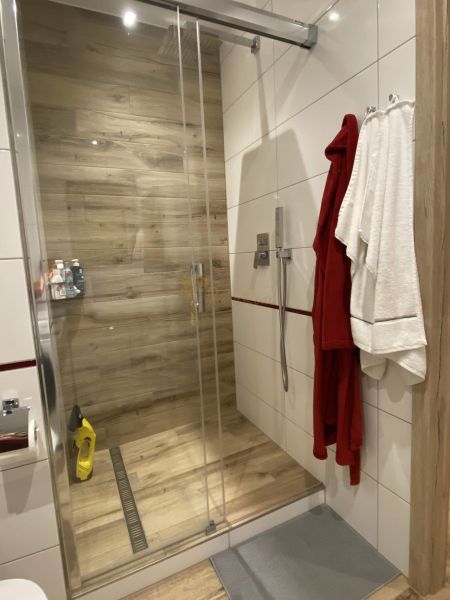 Bathroom with a shower, wooden decor flooring, and robe hooks in a 3-room apartment.