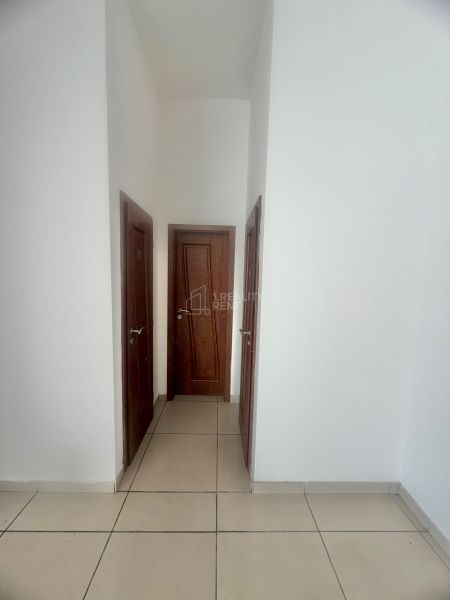 White walls with wooden doors and tiled floors in commercial spaces.