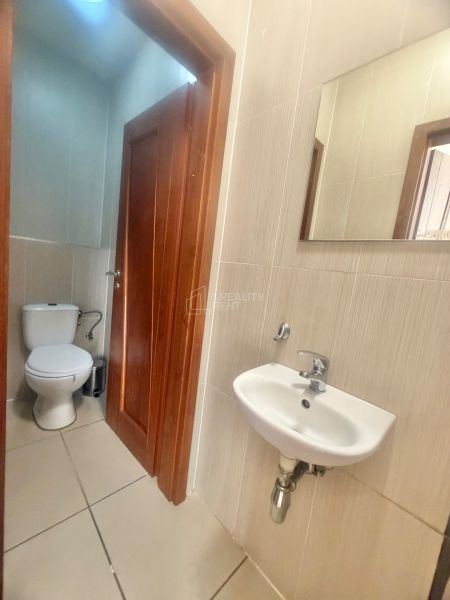 A small bathroom in commercial premises with a toilet, sink, and mirror.