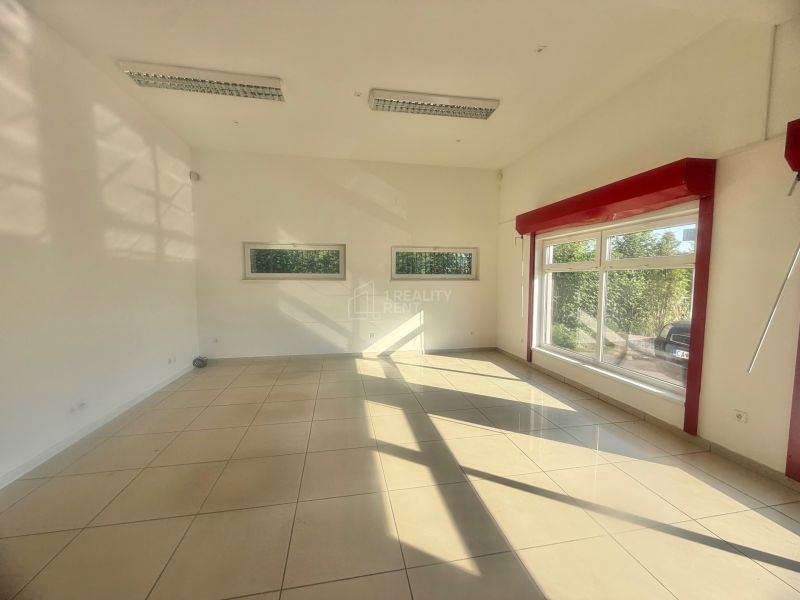 Interior of a commercial space with large windows and glossy tiles.