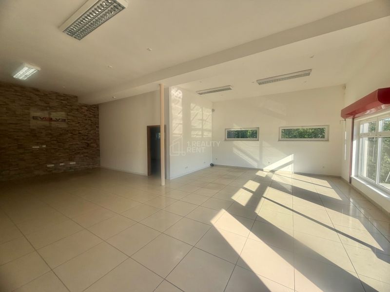 Spacious commercial spaces with large windows, white walls, and tiled floors.