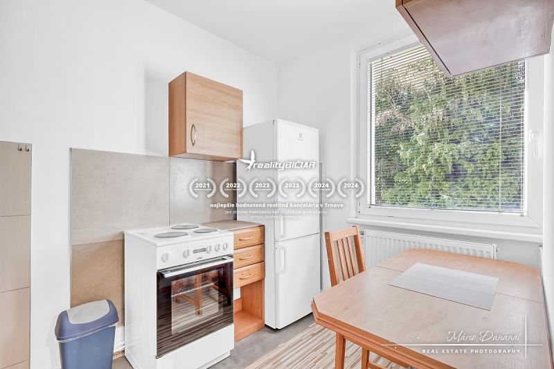 Kitchen in a studio apartment with a kitchenette, table, and refrigerator.