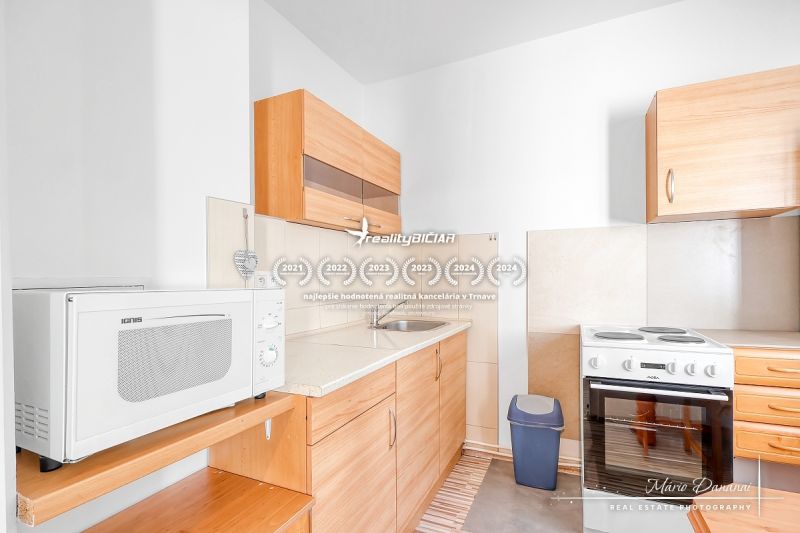 A kitchen in a studio apartment with wooden decor and a white microwave.