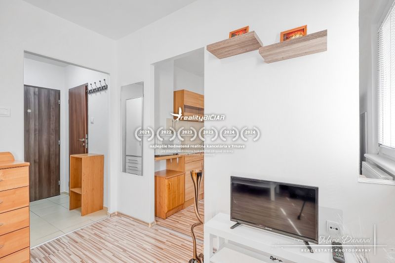 Interior of a one-room apartment with a wooden decor floor and light furniture.
