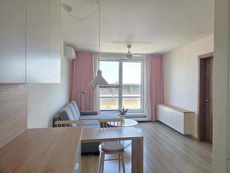 Living area of a 2-room apartment with a kitchen table and a wooden decor floor.