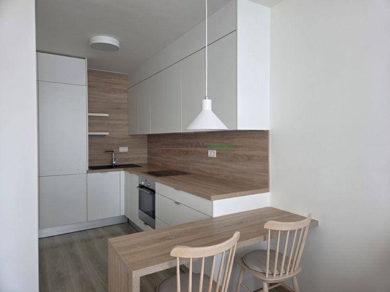 A kitchen with white cabinets and wooden decor in a two-room apartment.