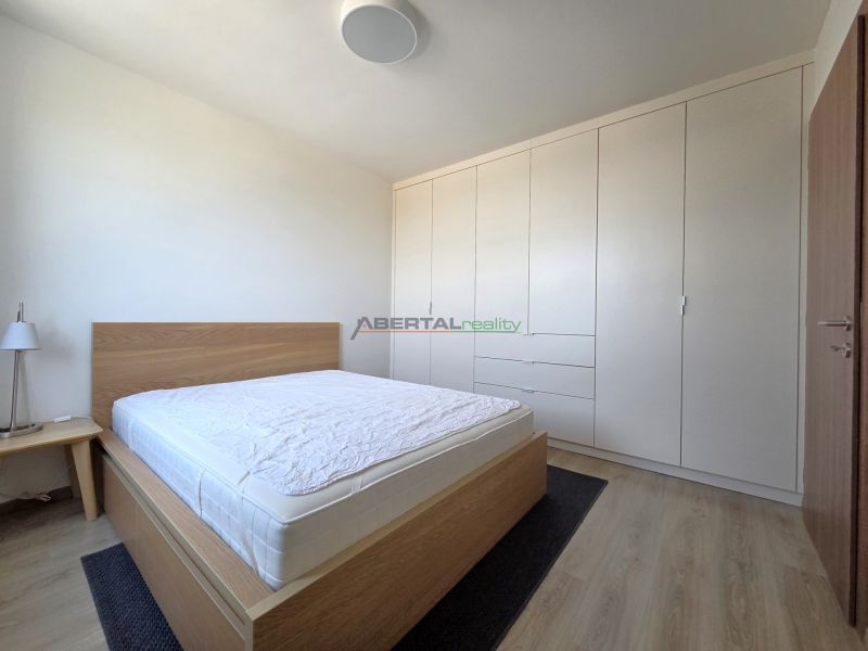A bright bedroom in a two-room apartment with a large built-in wardrobe and a bed.