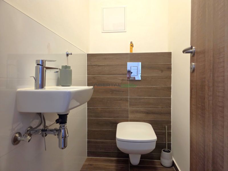 Cozy bathroom with a white sink and toilet, floor with wood decor.