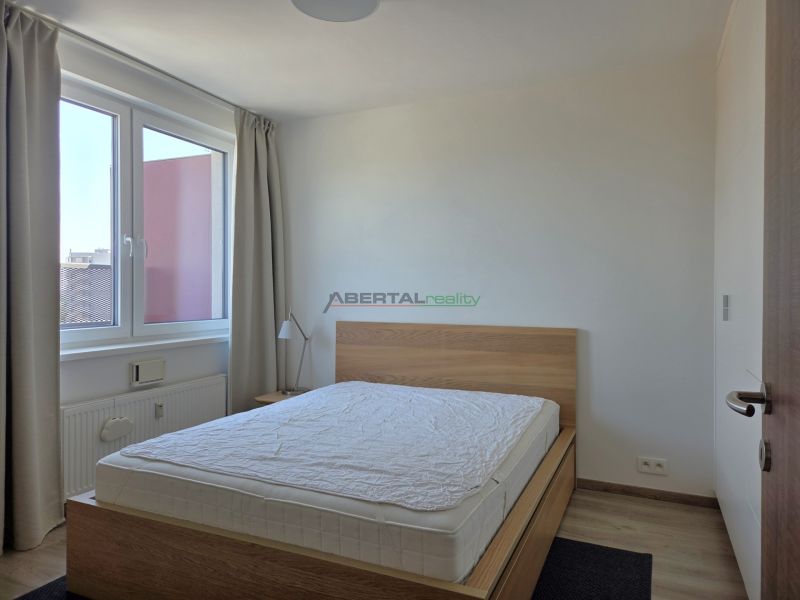 Bedroom in a 2-room apartment with a bed and a large window, floor with wooden decor.