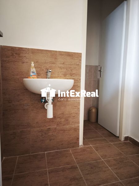 A sink with tile decor in commercial premises with a wooden decor floor.