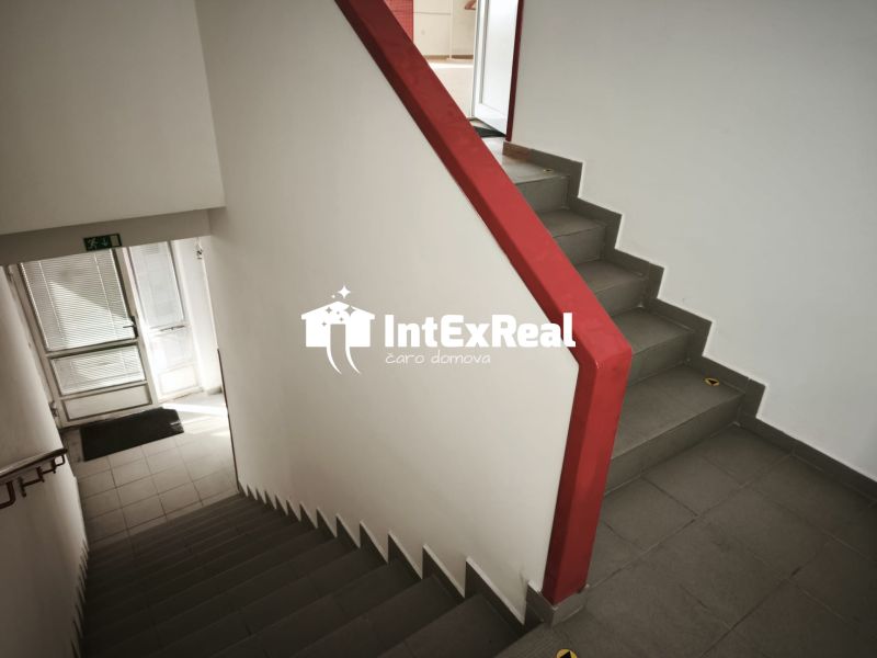A staircase with a red railing in commercial premises, tiled floor.
