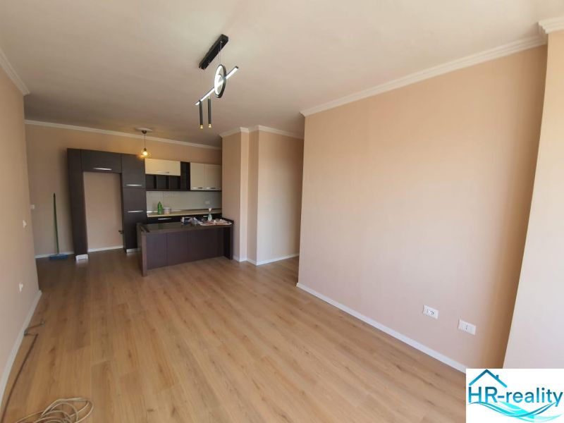 Living area with a kitchenette and a wooden decor floor in the Holiday Apartment.
