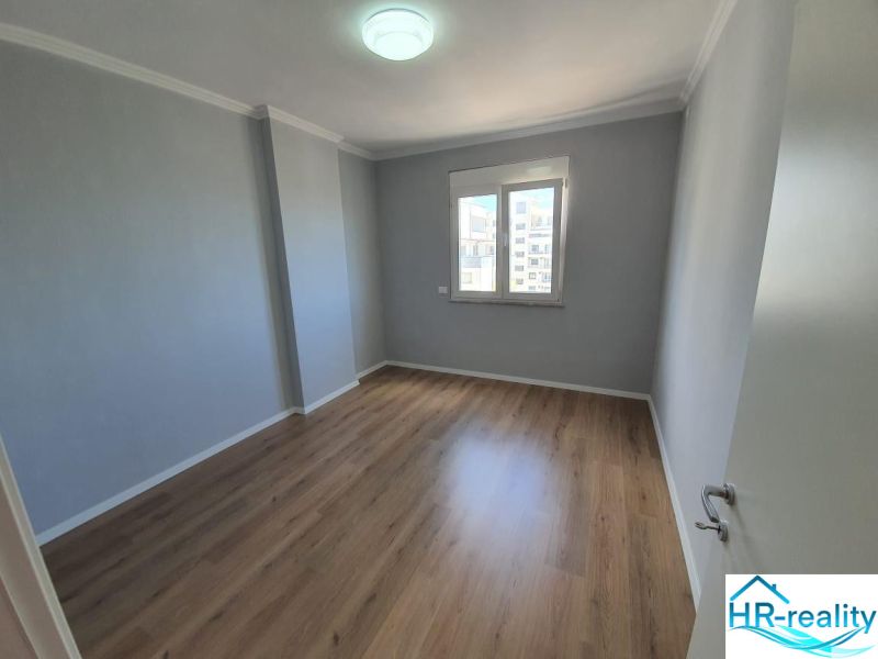 A room in a recreational apartment with a wood-patterned floor and a window.