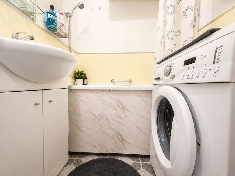 Bathroom with a bathtub, washing machine, and washbasin cabinet in a 3-room apartment.