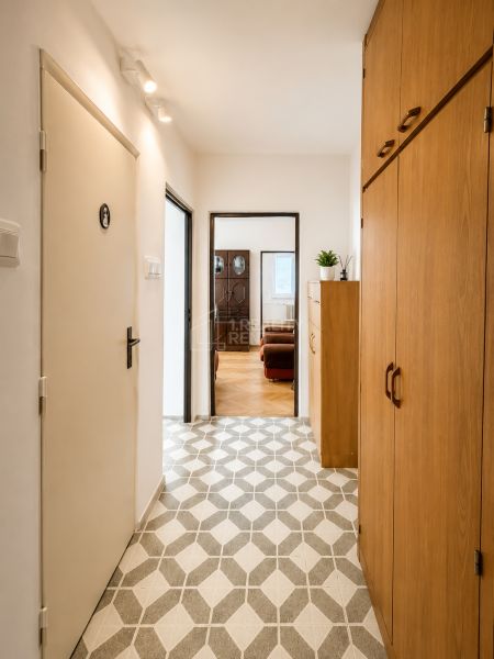 The hallway of a 3-room apartment with tiles and a built-in wardrobe leads to the living room.