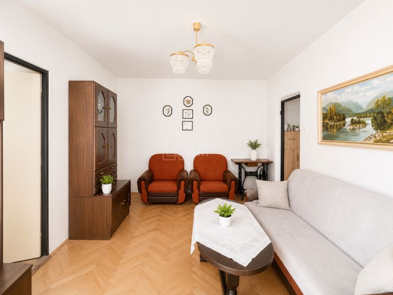 Living room with wood-patterned flooring, furniture, and paintings in a 3-room apartment.