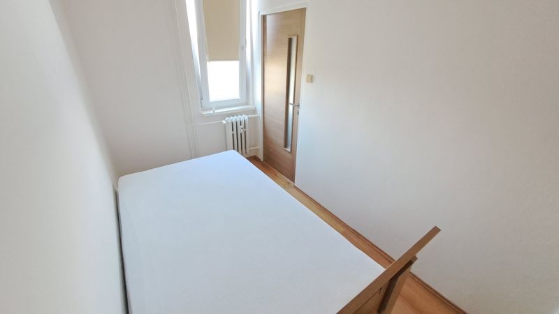 A bedroom with white walls and a wooden decor floor in a 2-room apartment.