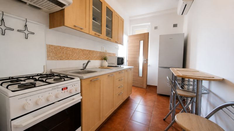 A kitchen in a 2-room apartment with wooden cabinets, a stove, and a dining table.