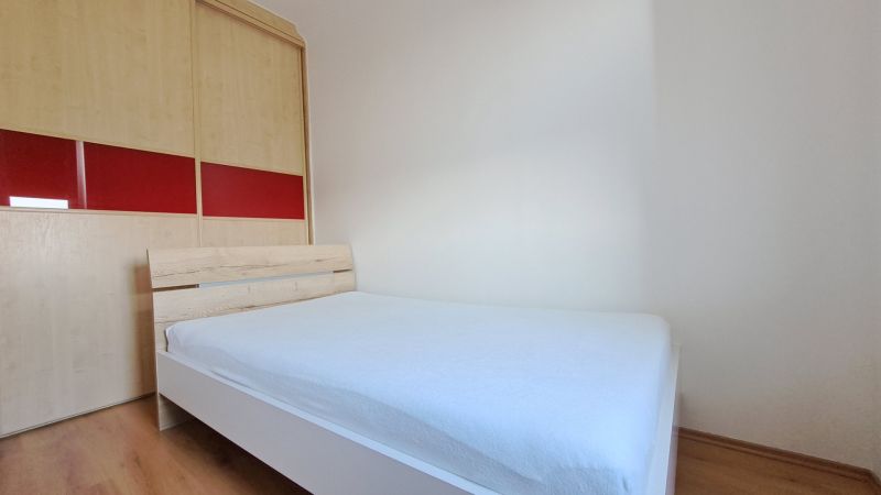 Bedroom with a bed and built-in wardrobe, 2-room apartment, floor with wood decor.