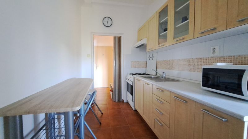 A kitchen in a 2-room apartment with a dining table and appliances.