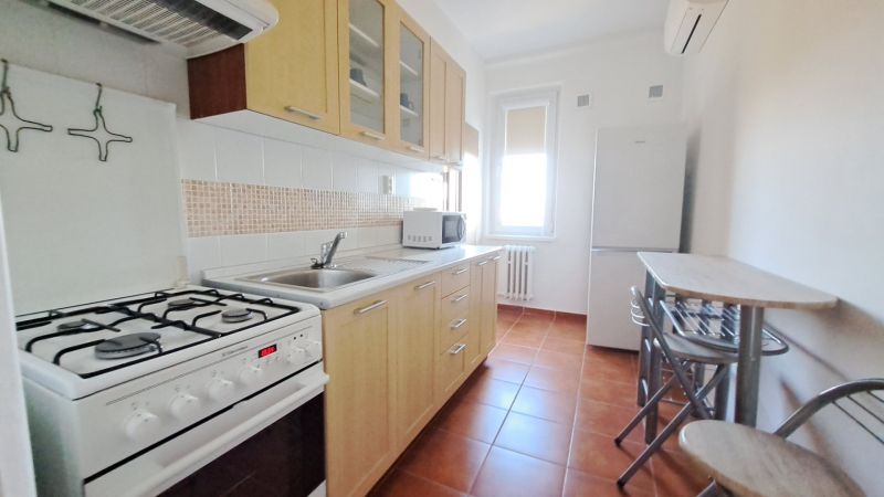 Kitchen in a 2-room apartment with a gas stove, sink, and dining table with chairs.