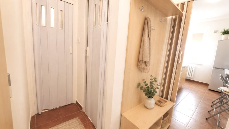 A hallway in a 2-room apartment with built-in wooden storage space and curtains.