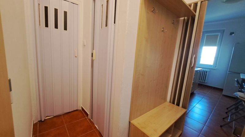 Entrance with brown tiles, a wardrobe, and sliding doors in a 2-room apartment.