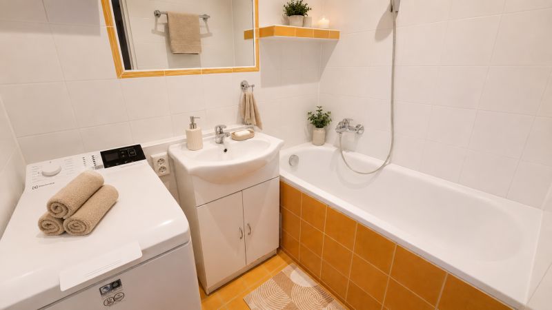 Bathroom with a bathtub, sink, washing machine, and decorative towels in a 2-room apartment.