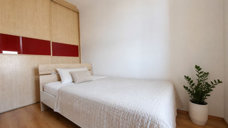 Bedroom in a 2-room apartment with wood-patterned flooring and a built-in wardrobe.