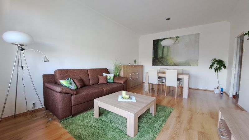 Living room with a sofa and a dining table in a 2-room apartment, floor with a wooden decor.