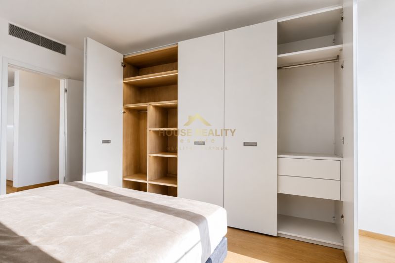 White built-in wardrobe with drawers and open shelves in a 3-room apartment, floor with wood decor.