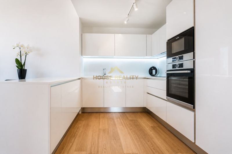 A kitchen in a 3-room apartment with white cabinets and a wooden-patterned floor.