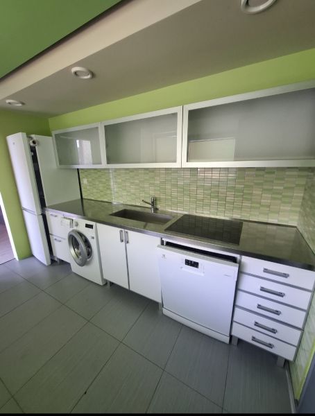 A kitchen in a 3-room apartment with white cabinets and green tiles.