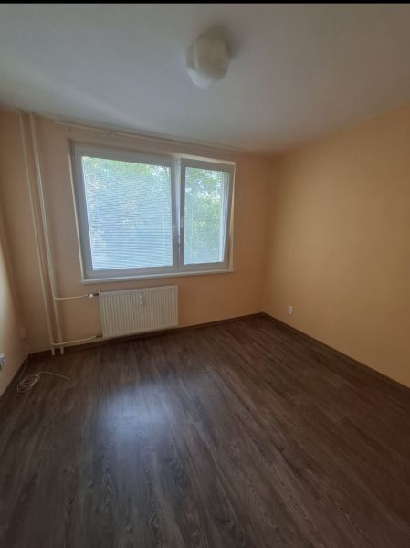 A room in a 3-room apartment with a wooden decor floor and a large window.