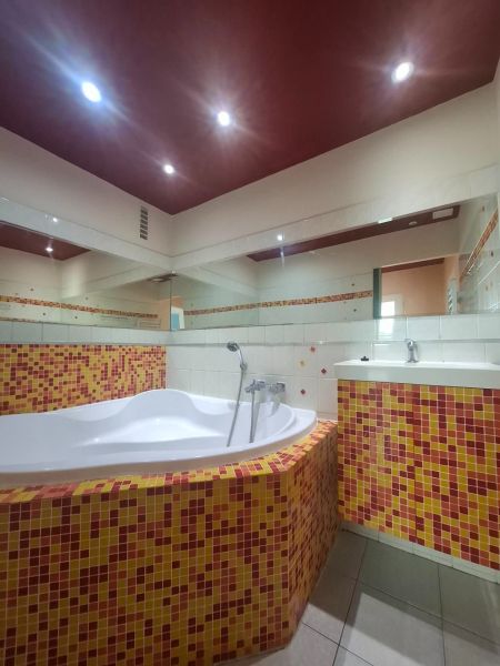 A bathroom with a bathtub tiled with colorful mosaic tiles in a 3-room apartment.