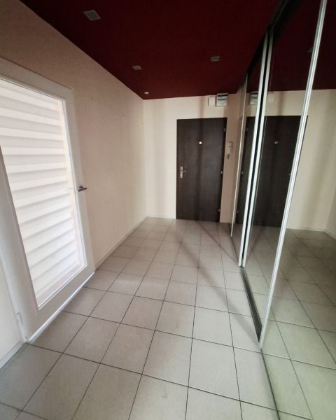 A hallway in a 3-room apartment with tiled flooring, a mirrored wardrobe, and dark doors.