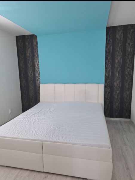 A bright bedroom with a white bed and a blue wall in a 3-room apartment.