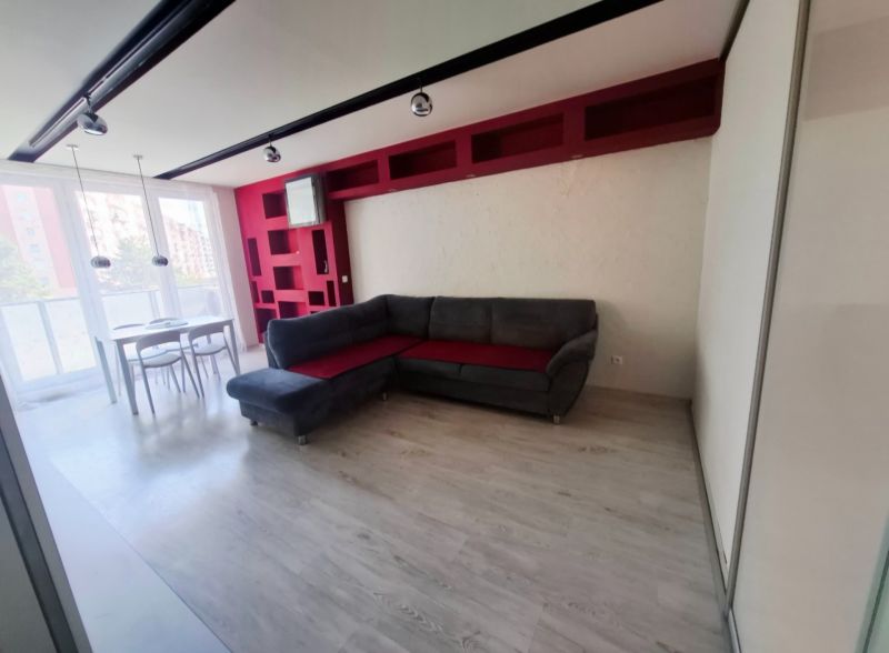 Living room in a 3-room apartment with a corner sofa, dining table, and floor with a wooden decor.