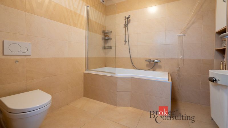 Bathroom with a bathtub and toilet in a family house with ceramic tiles.