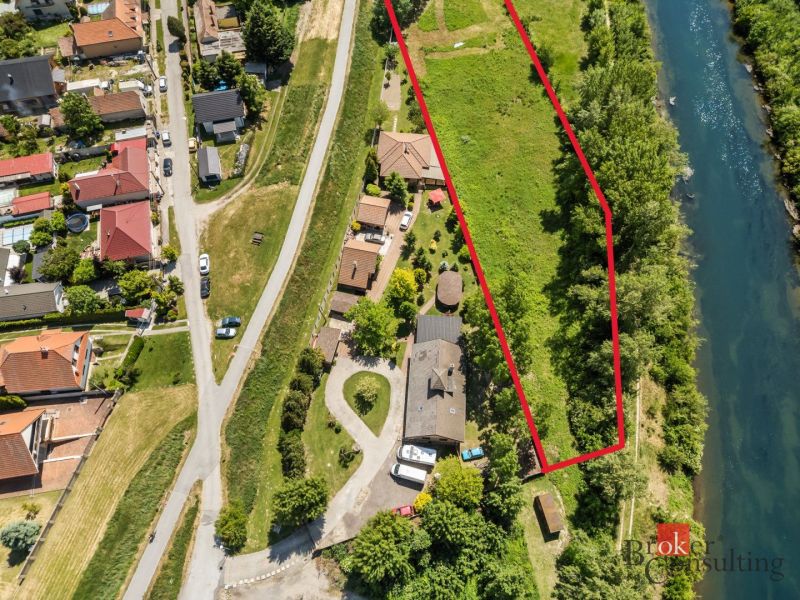 Recreational plots in Hamuliakovo by the river, surrounded by greenery and houses.
