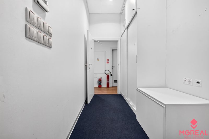 A corridor with white walls and a wooden decor floor in commercial premises.