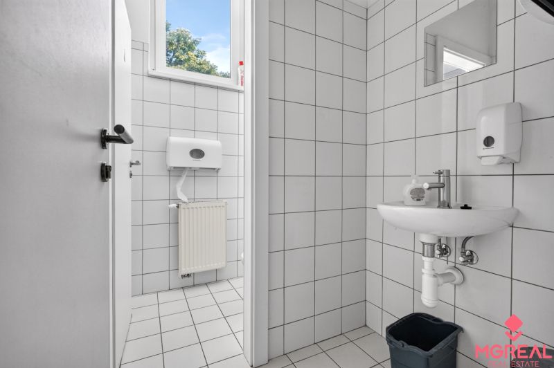 A restroom with white tiles and a sink in commercial premises.